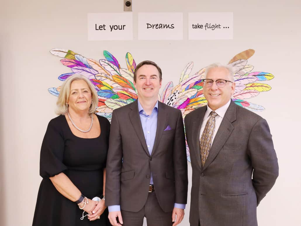 Jennifer McCue, President and CEO of Bethany Care Society, Jason Copping, Alberta Health Minister, and Dr. Al Kryski, Board Chair, Bethany Care Society stand together in front of a colourful mural.